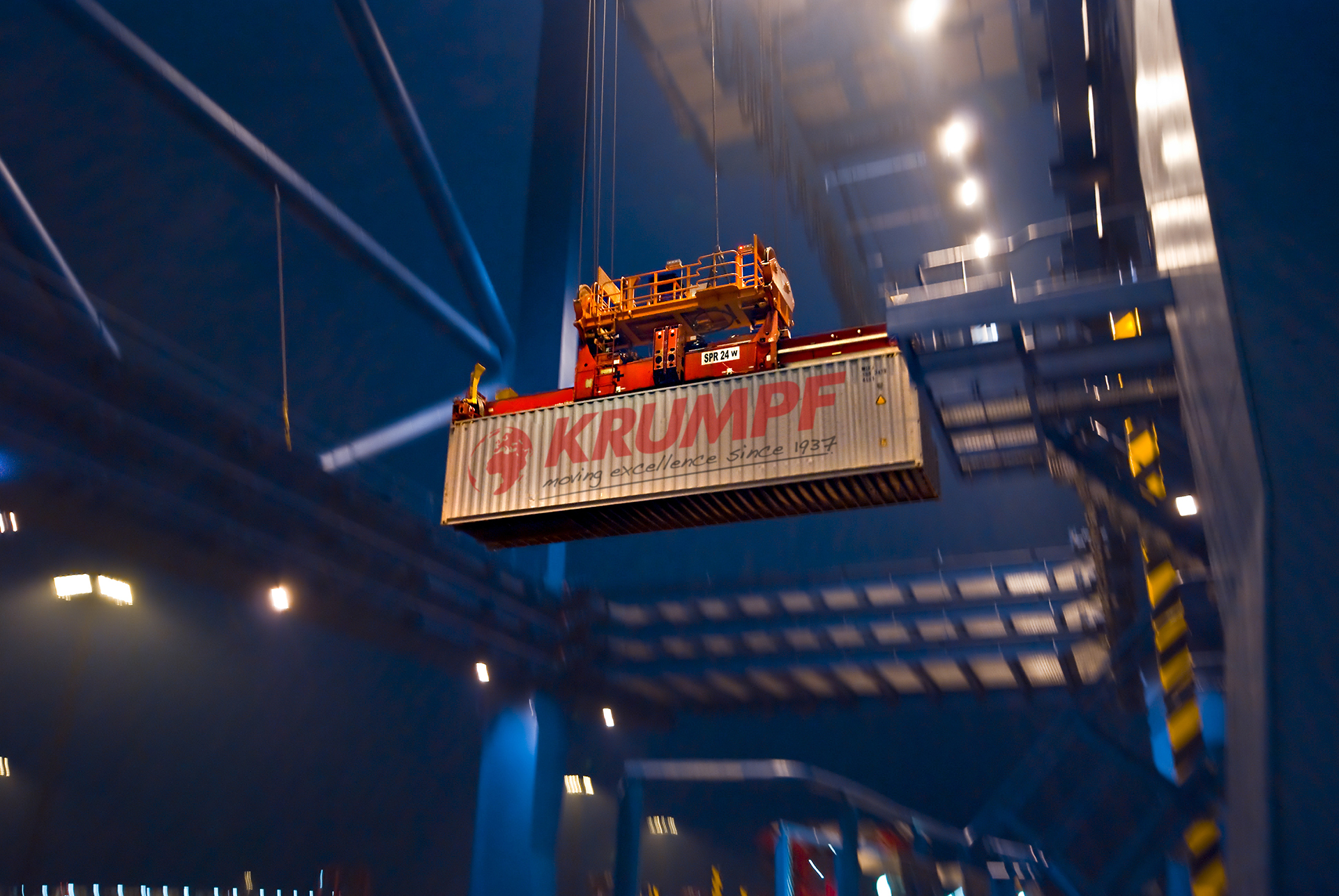Ein Schiffscontainer wird nachts auf einem Industriegelände von einem Kran angehoben. Dies zeigt die Effizienz von HANSETRANS als professionelles Umzugsunternehmen bei der Abwicklung schwerer Umzüge auch nach Einbruch der Dunkelheit.