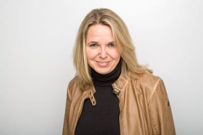 Eine Frau in Lederjacke lächelt während einer STADTBOTE-Veranstaltung in Hannover in die Kamera.