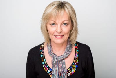 Eine Frau mit blonden Haaren trägt eine bunte Halskette aus Stuttgart.