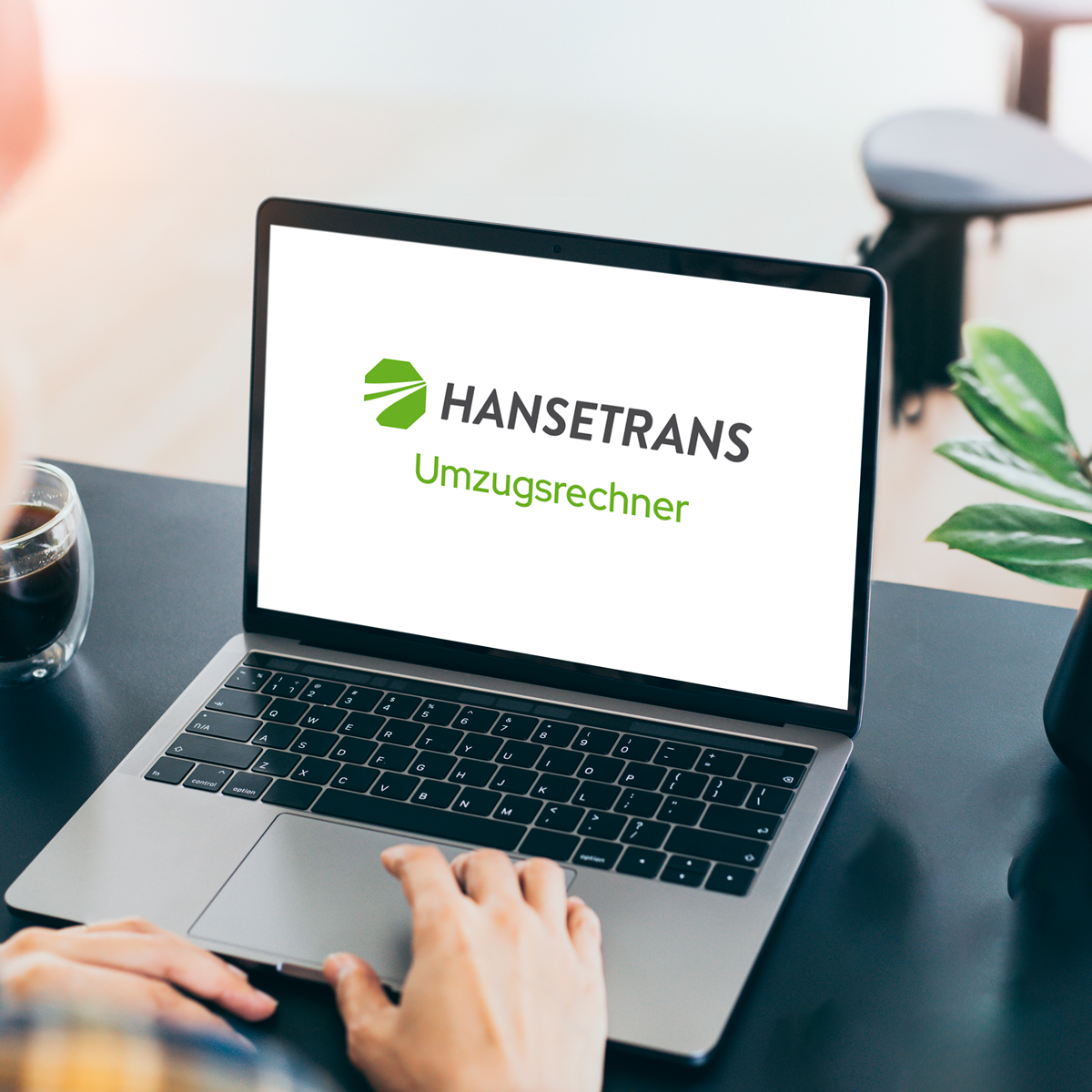 Auf einem Schreibtisch steht ein Laptop mit dem Logo des HANSETRANS Umzugsrechners, daneben eine Kaffeetasse.