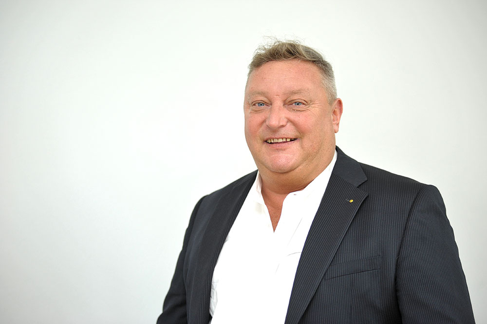 Ein Mann im Anzug und weißem Hemd lächelt bei der Präsentation eines Umzugsunternehmens in Dresden.
