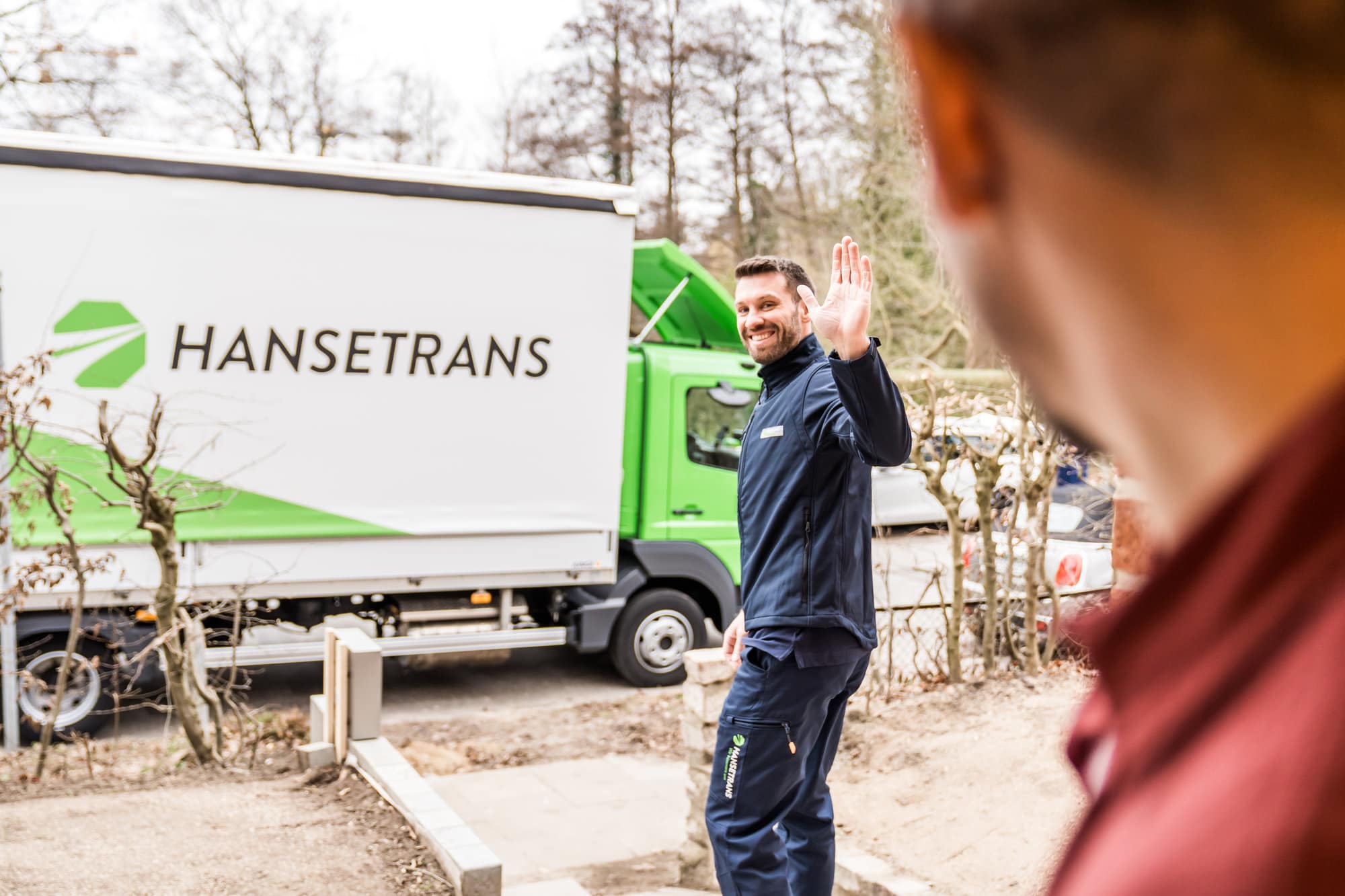 Ein Mann steht neben einem LKW mit der Aufschrift „hansetrans“, stellvertretend für einen Transportpartner.