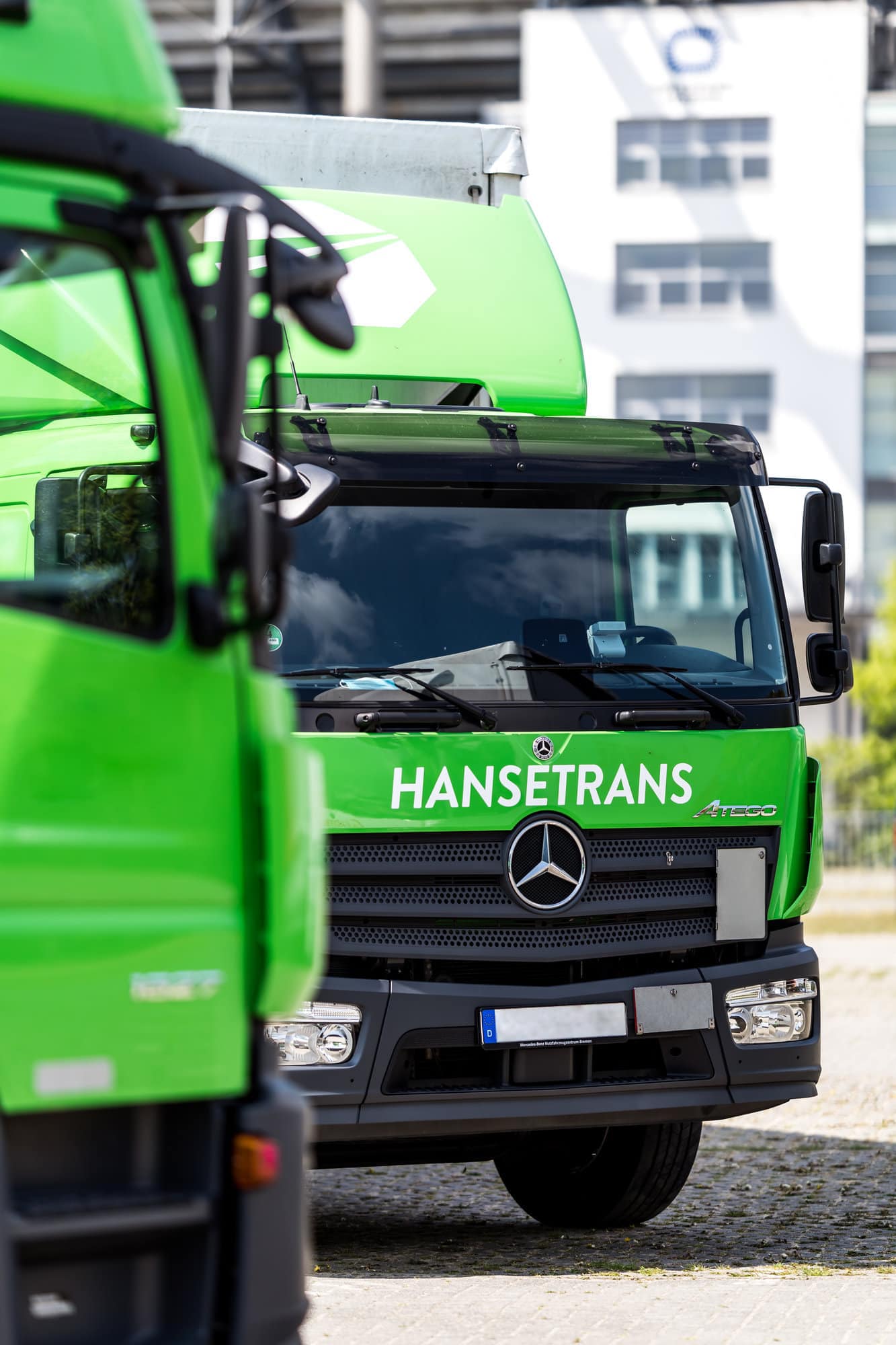 Ein grüner LKW, der als Transportpartner fungiert, parkt vor einem Gebäude.